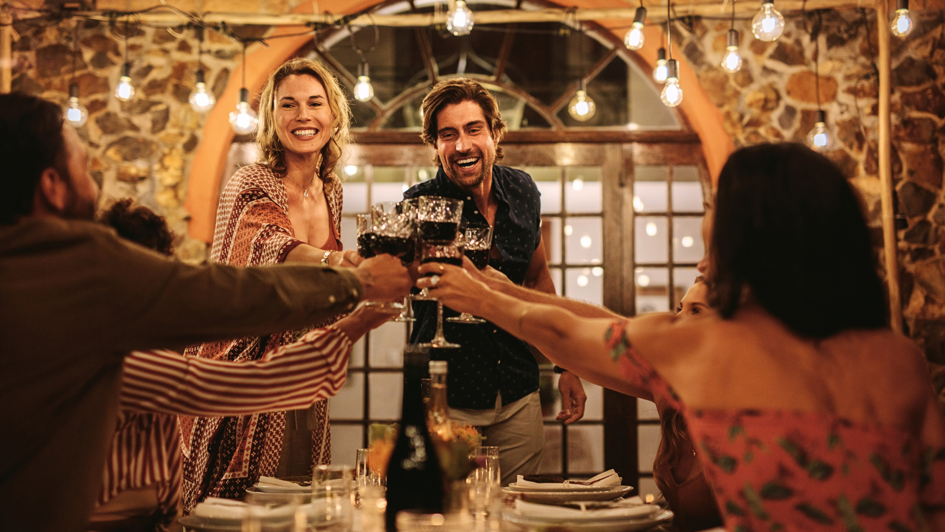 Friends raising glasses over dinner during a private event in Italy, example result of planning an event in Italy.