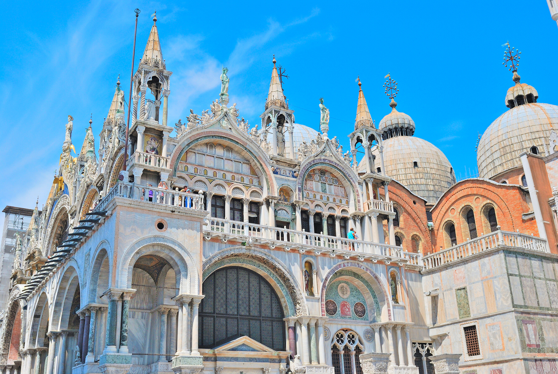 St. Mark’s Basilica in Venice viewed from Piazza San Marco beneath a bright blue sky.