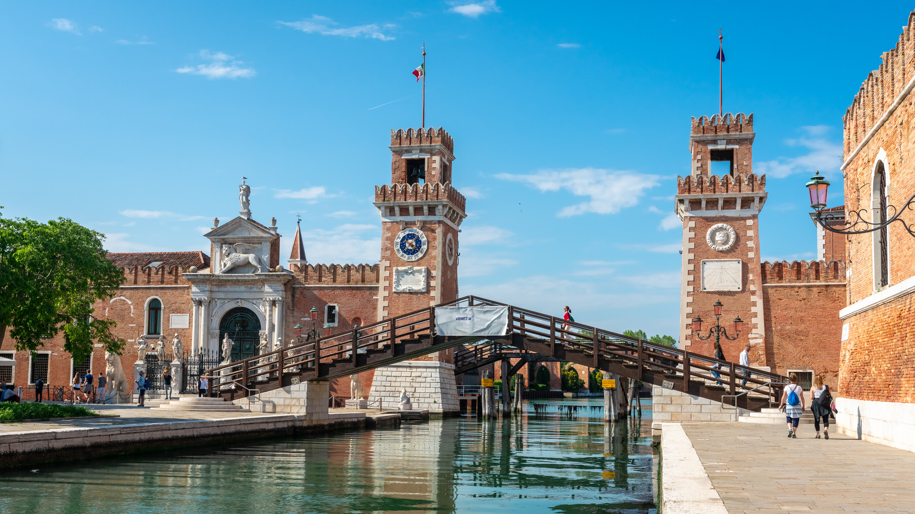 Entrance to the Venice Arsenale, with its twin brick towers and wooden bridge over a canal.